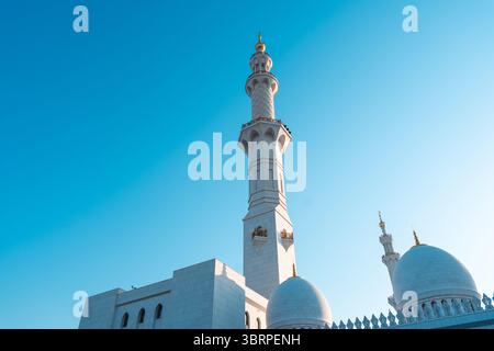 moschee in Abu Dhabi, hohes weißes Minarett mit komplizierten Schnitzereien vor blauem Himmel, Hintergrund des Kopierraums Stockfoto