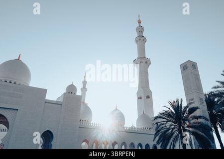 Minarette der Scheich-Zayed-Moschee vor dem Sonnenuntergang, große Moschee-Architektur mit Sonne dahinter Stockfoto