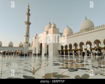Abu Dhabi Sheikh Zayed Moschee bei Sonnenuntergang, goldene Stunde Licht auf Moschee Kuppeln und Minarett, dekorative Säulen und Bögen in der Moschee - horizontaler Bogen Stockfoto