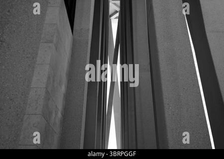 Abstrakte Ansicht einer modernen Architekturstruktur mit sich kreuzenden Balken und vertikalen Linien. Schatten spielen auf Betonflächen Stockfoto