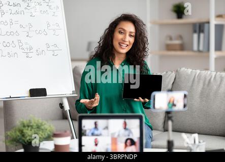 Lehrerin erklärt Mathematik online und zeigt Tablet auf Laptop Stockfoto