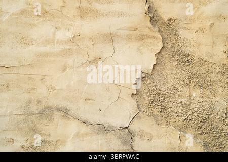 Hintergrund der alten Gebäudewand mit abgebrochenen Farben und Putzrissen, Kalksteinwand mit Rissen Stockfoto