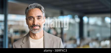 Glücklicher, reifer Geschäftsmann mittleren Alters, der im Büro die Kamera ansieht. Stockfoto