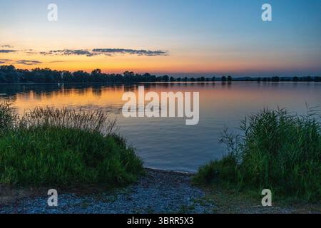 Segelschiffe im Hafen von Hard am Bodensee vor Sonnenaufgang beleuchtet die Dämmerung den See und zaubert intensive Farben auf das Wasser Stockfoto