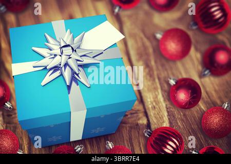 Vektorgrafik mit blauer Geschenkbox mit weißem Band, silberner Schleife, roten Kugeln auf Holztisch Stockfoto