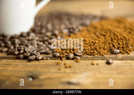 Kaffeebohnen verschütten neben gemahlenem Kaffee auf rustikalem Tisch und verschwommenem Becher in flachem Design Stockfoto