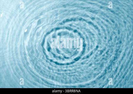 Blauer Hintergrund mit Wasserstruktur. Reinigen Sie die transparente Wasseroberfläche mit Ringen und Wellen. Sommerkonzept. Flache Lagen Stockfoto