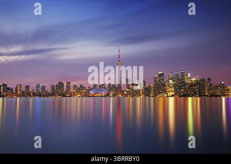 Aus der Vogelperspektive die beleuchtete Stadtlandschaft reflektiert auf dem ruhigen Wasser, dominiert vom CN Tower und Rogers Centre vor einem Abendhimmel, Toronto, Ontario, Kanada. Stockfoto