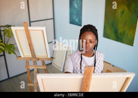 Junge Erwachsene Schwarze Frau Malerei auf Leinwand im Kunststudio drinnen Stockfoto