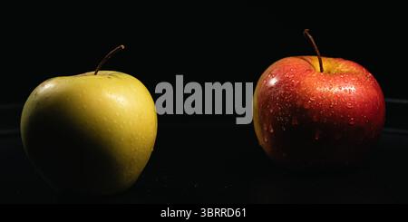 Rote und gelbe Äpfel mit Wassertropfen auf schwarzem Hintergrund Stockfoto