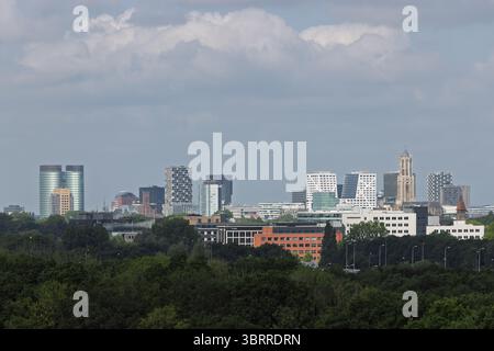 Ein Panoramablick auf die Skyline von Utrecht mit modernen Hochhäusern und dem berühmten Dom Tower, der über eine üppig grüne Baumlinie hinausragt Stockfoto