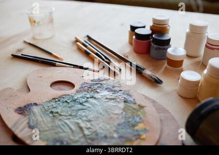 Nahaufnahme von Kunstzubehör und Pinseln, die auf einer Holzplatte angeordnet sind Stockfoto
