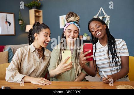 Multiethnische junge Erwachsene Frauen lächeln, während sie Selfie mit Smartphones nehmen Stockfoto