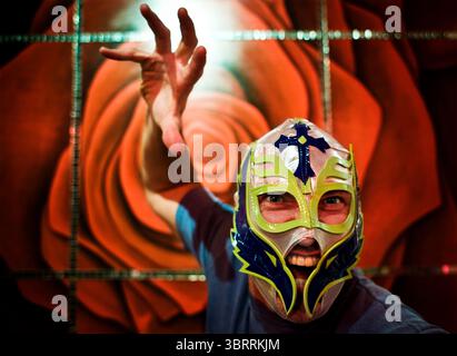 Ein Mann posiert vor einem Wandgemälde, während er eine lucha libre mexikanische Wrestling Maske in Cancun, Mexiko, trägt. Stockfoto