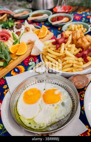 Lebhaftes türkisches Frühstück mit sonnigen Eiern, frischem Obst, Pommes Frites und verschiedenen Gebäckstücken Stockfoto