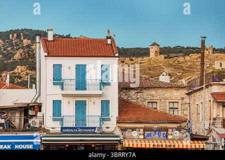 7. Mai 2025, Foca, Turkiye: Malerischer Blick auf ein Küstendorf mit traditioneller Architektur, farbenfrohen Fassaden und historischen Windmühlen Stockfoto