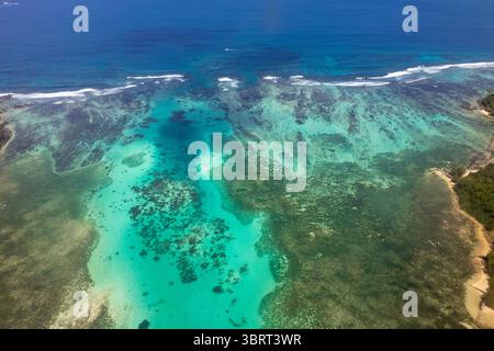 Ein Blick aus der Vogelperspektive fängt das pulsierende türkisfarbene Wasser und die Korallenriffsysteme der Seychellen hoch über der wunderschönen Küste ein. Stockfoto