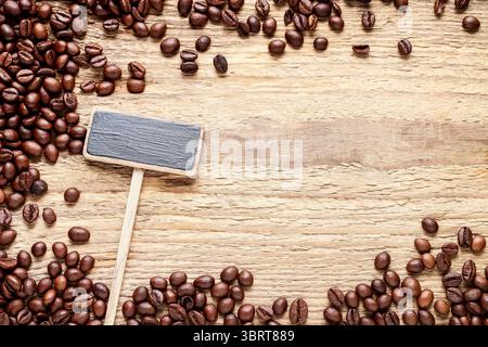 Leeres Tafelschild und Kaffeebohnen isoliert auf hölzernem Hintergrund, Kopierraum Stockfoto