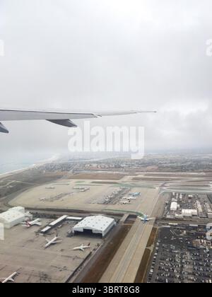 17. Mai 2025 - Los Angeles, CA, USA - Ein Blick aus dem Bullauge eines Flugzeugs mit Blick auf die Start- und Landebahn und die Ladelogistik Stockfoto