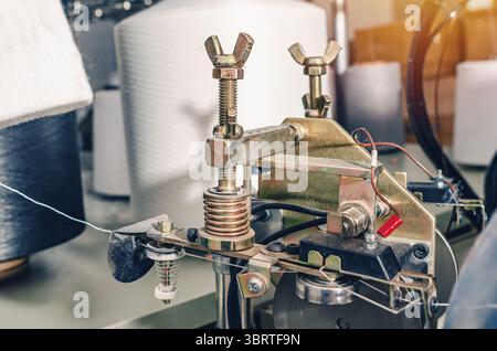 Gewindespanner befinden sich an den Schiebern der Maschinen. Industrieunternehmen zur Herstellung von Socken. Detailansicht Stockfoto