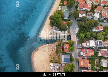 Kleine Küstenstadt trifft auf das türkisfarbene Meer unter einer hellen Sonne und bietet einen Blick aus der Vogelperspektive voller lebendiger Farben und heiterer Schönheit Stockfoto