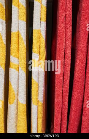 Zwei Handtücher, ein gelbes und ein rotes, hängen nebeneinander. Das gelbe Handtuch hat ein Muster von Quadraten und das rote Handtuch hat ein Muster von Kreisen. Ve Stockfoto