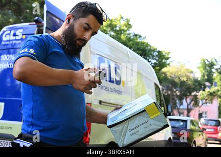 Düsseldorf, Deutschland. Juli 2025. Ein Paketdienstleister des Paketdienstleisters GLS steht vor seinem Elektrobus und scannt eine wiederverwendbare Kiste, um sie zuzustellen (posierte Szene). Die wiederverwendbare Box stammt vom Münchner Start-up Hey Circle. Diese wiederverwendbaren Kisten sollen Papppaketverpackungen ersetzen, die normalerweise weggeworfen werden und zu großen Müllbergen führen. Quelle: Wolf von Dewitz/dpa/Alamy Live News Stockfoto