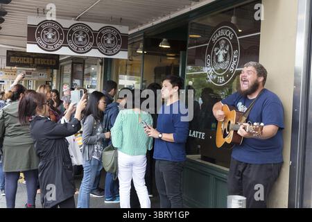 13. Juni 2018: Seattle, Washington, Vereinigte Staaten - Seattle, Washington: Eine Menge Touristen stürmt in den Pike Place Starbucks Store, während ein Busker in der Nähe singt. Dieses Café, das allgemein als das ursprüngliche Starbucks bekannt ist, befindet sich seit 1976 an seinem heutigen Standort und hat einen Großteil des frühen Erscheinungsbildes erhalten. Das erste Starbucks Café befand sich zwischen 1971 und 1976 auf der Western Avenue. (Bild: © Paul Gordon via ZUMA Wire) Stockfoto