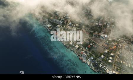 Aus der Vogelperspektive auf eine Küstenstadt, wo türkisfarbenes Wasser in flauschigen Wolken auf das Land trifft und ein ruhiges und dennoch lebendiges Panorama schafft, Kralendijk, Bonaire, Karibik Niederlande. Stockfoto