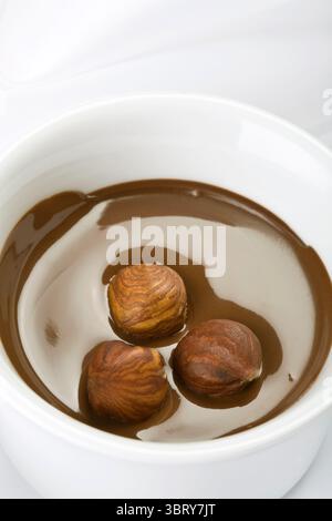 Zubereitung von Kakaogetränk im Glas, Hinzufügen von Milch zu Kokaenergie von oben auf weißem Hintergrund Stockfoto