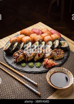 Sushi-Set auf schwarzem Schiefer mit Sojasauce, eingelegtem Ingwer und Wasabi Stockfoto