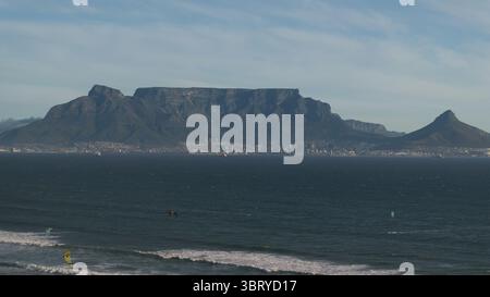 Aus der Vogelperspektive auf den Tafelberg, der majestätisch über der Stadt steht, während die Meereswellen auf das Ufer stürzen, eine Mischung aus Naturwunder und urbanem Leben, Kapstadt, Westkap, Südafrika. Stockfoto