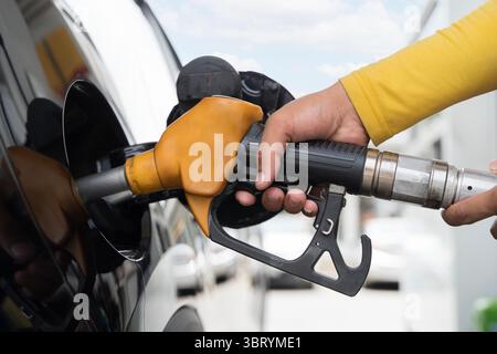 Nahaufnahme der Hand, die die Kraftstoffdüse hält, die Benzin an der Tankstelle in das Auto pumpt. Konzept für Betanken, Transport, Energie, Öl, Kraftstoffverbrauch, reisen Stockfoto
