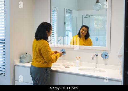 Asiatische Frau, die Hände über zwei Waschbecken Waschbecken im Badezimmer mit Seifenschale und Kopierraum wäscht Stockfoto
