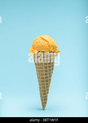 Orangefarbener Eiskegel isoliert auf blauem Hintergrund. Stockfoto
