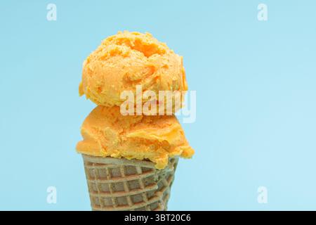 Orangefarbener Eiskegel isoliert auf blauem Hintergrund. Stockfoto