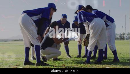 Ein kuscheliges Softball-Team, das dem Trainer beim Knien mit Klemmbrett im Außenfeld zuhört, blaue Trikots und Handschuhe Stockfoto