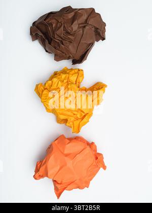 Braune, orangefarbene und gelbe zerknitterte Papierkugeln, die vertikal angeordnet sind Stockfoto