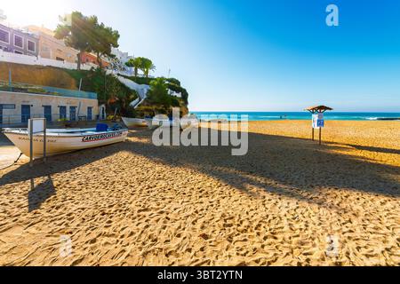 Boote sitzen am Sandstrand Praia de Carvoeiro im Dorf Carvoeiro, einem kleinen Fischerort am Meer in der Algarve in Portugal. Stockfoto