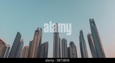 Blick auf die Architektur der Dubai Marina Skyline von unten, von oben nach unten mit blauem Himmel bei Sonnenuntergang Stockfoto