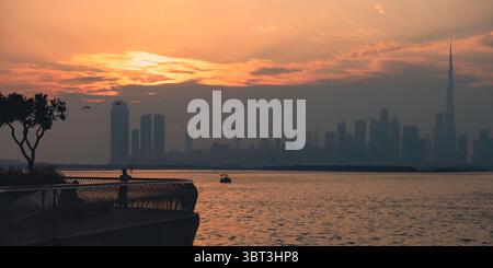 Malerischer Sonnenuntergang hinter der Skyline von Dubai, Blick vom Hafen des Dubai Creek, bester Sonnenuntergang in Dubai 2025 Stockfoto
