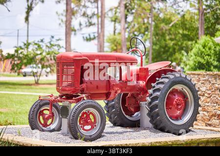 Central Park in der Gemeinde Lakeland, GA USA, mit einer Bogenbrücke über einen Teich, der United States Flag und einem alten internationalen Traktor! Stockfoto