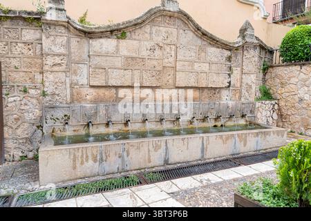 Brihuega feiert das Lavender Festival, bei dem Besucher einen historischen Brunnen bewundern. Das Wasser fließt aus mehreren Ausläufen, umgeben von wunderschönen Steinen Stockfoto