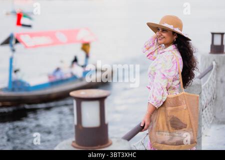 Junge Frau, die den Blick auf den Bach von Al seef mit Abra Booten und der Altstadt von Dubai genießt Stockfoto