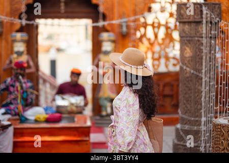 Eine junge Frau in ethnischer Kleidung und Hut erkundet das historische Viertel Al Seef in Dubai, umgeben von traditioneller emiratischer Architektur und kultureller Atmosphäre Stockfoto