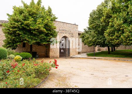 Besucher bewundern die bezaubernde Steinarchitektur in Brihuega, umgeben von üppigem Grün und lebhaften Rosen. Diese ruhige Gegend zeigt die Schönheit von Sp Stockfoto