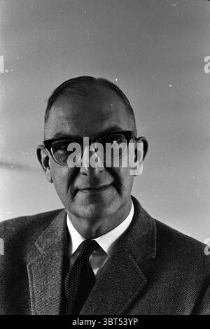 Bürgermeister Peereboom-Voller von Bloemendaal Herr J.H.W.Buckerman Personen, Whizgle News, Dutch Desk, Niederlande, 1950 - 2000 am 19.12.1962. Diese Themen werden in der Abbildung angezeigt. Die Szene zeigt einen Mann mittleren Alters mit einem würdevollen Ausdruck, eingerahmt vor einem weichen, gedämpften Hintergrund, der seine Präsenz unterstreicht. Er hat ordentlich gekämmte Haare und trägt eine große rechteckige Brille, die sein wissenschaftliches Aussehen unterstreicht. Sein Gesicht vermittelt einen Hauch von Intelligenz und Selbstvertrauen und zeigt subtile Alterserscheinungen wie schwache Linien um Augen und Mund. Er trägt einen hellen Blazer über einem dunklen Kragen Stockfoto
