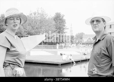 Zwei Architekten Heemskerk (in der Nähe des Teichs auf Zaalberglaan) Heemskerk Zaalberglaan, Whizgle News, Dutch Desk, Niederlande, 1950 - 2000 am 24-06-1994. Die Abbildung zeigt diese Themen. Die Szene zeigt zwei Personen, die im Vordergrund stehen, beide in hellen, sommerlichen Kleidern, die auf einen warmen Tag hindeuten. Die Frau, die einen breitkrempigen Hut trägt, der einen Schatten über ihr Gesicht wirft, hat ihre Augen geschlossen, was ein Gefühl der Entspannung oder Besinnung vermittelt. Ihre Bluse scheint eine weiche Farbe zu sein, und sie ist mit einem Gürtel versehen, der ihrem Outfit einen Hauch von Stil verleiht. Neben ihr trägt ein Mann eine hellere Farbe Stockfoto