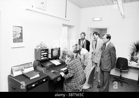 Eröffnung der Station Haarlem Eröffnung der Öffnungen Inbetriebnahme Station Haarlem Niederlande, Whizgle News, Dutch Desk, Niederlande, 1950 - 2000 am 11-05-1989. Die Abbildung zeigt diese Themen. In einem hell beleuchteten, modernen Bürobereich versammelt sich eine Gruppe von fünf Personen um einen Schreibtisch mit einem Vintage-Computer. Die Wände des Raumes sind in einem sauberen weiß gestrichen, was ein Gefühl von Offenheit und Einfachheit vermittelt, verstärkt durch die obenliegende fluoreszierende Beleuchtung, die eine gleichmäßige Helligkeit über die Szene verteilt. In der Mitte konzentriert sich eine Frau am Schreibtisch auf den Computerbildschirm. Sie trägt einen Stockfoto
