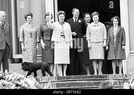 Geburtstag Ihre Majestät die Königin Juliana Royal Geburtstage, Whizgle News, Dutch Desk, Niederlande, 1950 - 2000 am 01-05-1961. Das Bild enthält diese Themen. Eine Gruppe von Einzelpersonen steht auf einer Reihe von Stufen, die zu einem kunstvollen Eingang führen. Die Umgebung strahlt eine formelle Atmosphäre aus, die wahrscheinlich mit einem historischen oder zeremoniellen Ereignis verbunden ist. Im Vordergrund zeigt eine Frau, die in einem hellen, maßgeschneiderten Anzug gekleidet ist, mit der rechten Hand, als würde sie ein Publikum begrüßen. Sie strahlt Selbstvertrauen und Wärme aus. Neben ihr steht ein Mann mittleren Alters in dunklem Anzug und Brille mit einem komponierten Auftreten und hält ein f Stockfoto